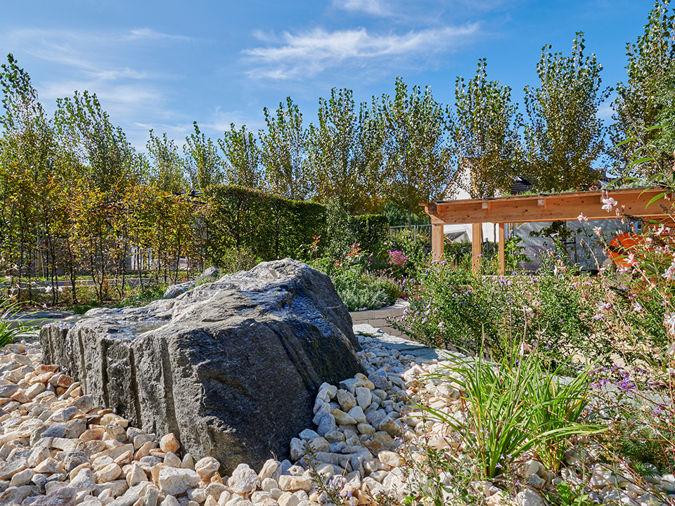 Senkgarten mit Natursteinen, Pflanzen und einer Holzpergola + begrüntem Dach